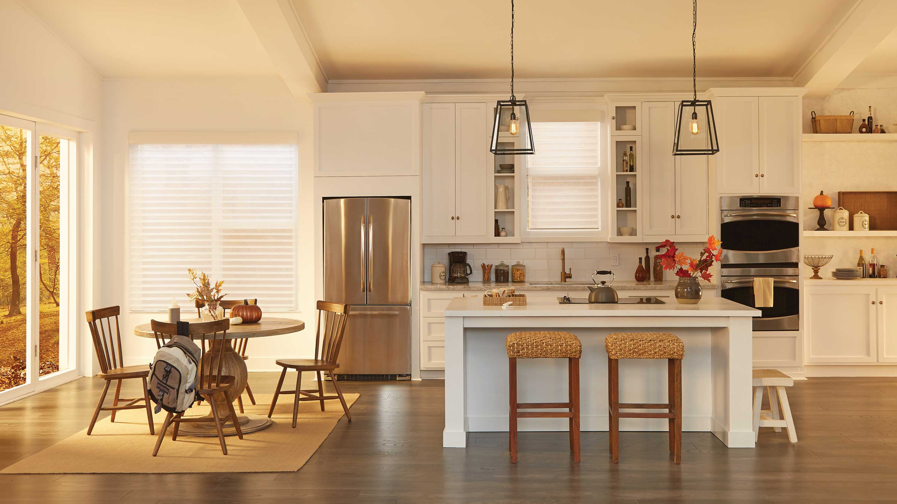 A kitchen with motorized shades lowered on windows.
