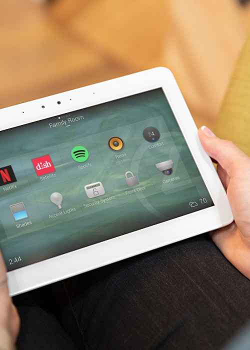 Person holding a tablet with the Control4 smart home interface. 