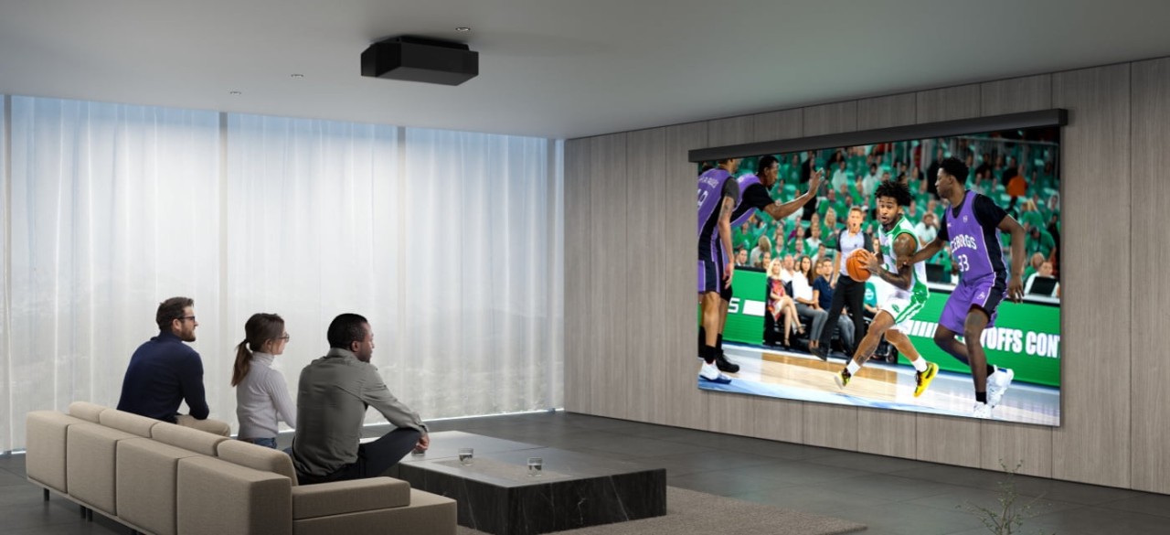 Three friends watch a basketball game displayed by a Sony projector in a home movie theater. 